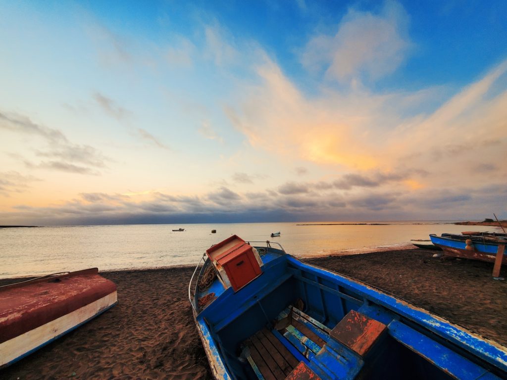 barco azul y rojo en la playa durante el día